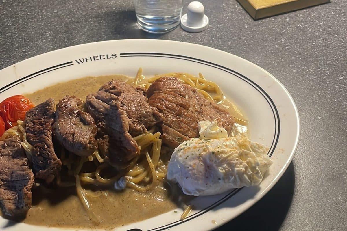 A plate of steak and noodles on a restaurant table