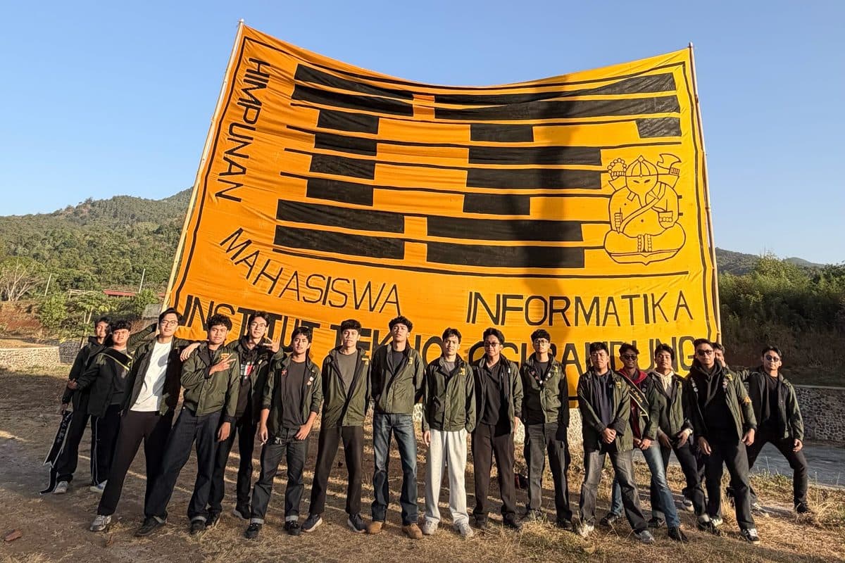 Informatics students posing with a giant banner on a hill